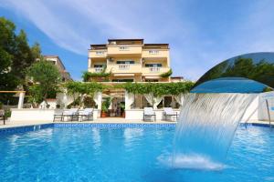 a pool with a water fountain in front of a building at Pansion Villa Bok in Novalja