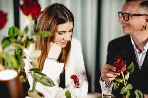 a man and a woman sitting at a table with a rose at Schwarzes Rössl in St. Wolfgang