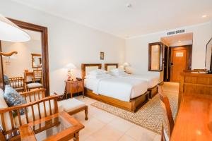 a bedroom with a large bed and a dining room at Ramayana Suites and Resort in Kuta