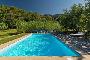 una piscina azul con sillas y árboles en El Rafalet, en Pollensa