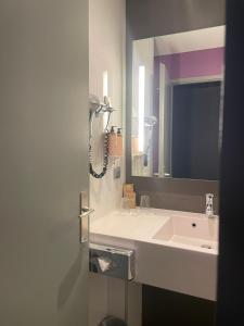 a bathroom with a sink and a mirror at Hotel Mercure Grenoble Centre Président in Grenoble
