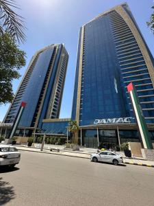 DAMAC Riyadh - Luxury Apartments في الرياض: مبنيان طويلان مع سيارات متوقفة أمام شارع