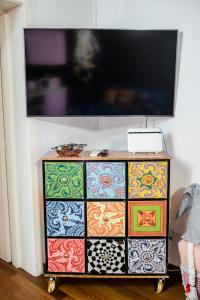 a colorful dresser with a flat screen tv on top at PINK HOUSE TORTELLINOSUITE Modena in Modena