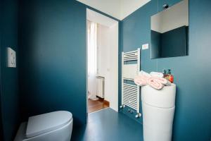 a bathroom with a toilet and a blue wall at PINK HOUSE TORTELLINOSUITE Modena in Modena