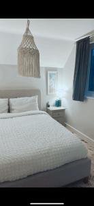 a bedroom with a white bed and a chandelier at Luxury HomeStays - Hot Tub - Sea Views - Sleeps 8 in Portsmouth