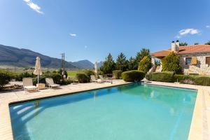a large swimming pool in front of a house at Pleiades All Season Gems - Korinthos Stone Retreats in Kalianoi