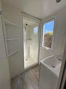 La salle de bains blanche est pourvue d'une douche et d'une fenêtre. dans l'établissement Camping le Moulin de la Salle, à Les Sables-dʼOlonne