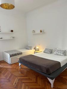 ミラノにあるAldebaranの白い壁とウッドフロアの客室で、ベッド2台が備わります。