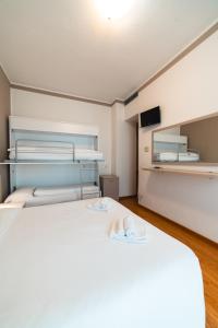 een slaapkamer met een groot wit bed en een tv bij Hotel Del Corso in Bibione
