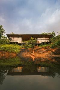 a woman sitting on a rock next to a body of water at Kurunduketiya Private Rainforest Resort in Kalawana