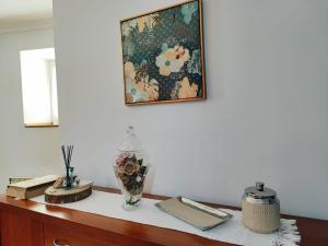 einen Schreibtisch mit einem Gemälde an der Wand und einer Vase in der Unterkunft Casinha do Sossego in Melgaço