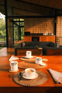 una mesa con tazas y platos encima en Kurunduketiya Private Rainforest Resort, en Kalawana