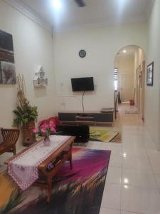 uma sala de estar com uma mesa e uma televisão em Jalinan Qaseh Homestay em Seri Manjung