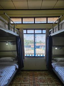 two bunk beds in a room with a window at Kai Lions International Hostel in Paksong