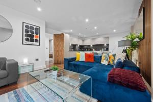 One Cambridge Residence by COQOON في مانشستر: غرفة معيشة مع أريكة زرقاء وطاولة زجاجية
