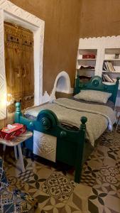 Schlafzimmer mit einem grünen und weißen Bett und einem Tisch in der Unterkunft نُزُل تُراثي شقْراء Heritage Guesthouse Shaqra in Shaqra