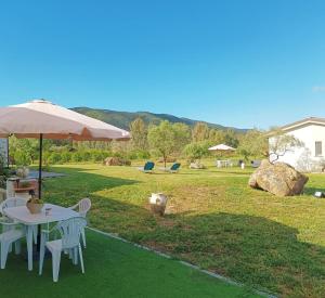 een tafel en stoelen met een parasol in de tuin bij B&B Sensorial Experience in Villamassargia
