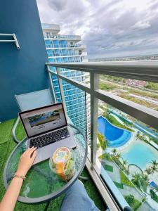 a person sitting at a table with a laptop on a balcony at Deluxe Dream - Azure North in Maimpis