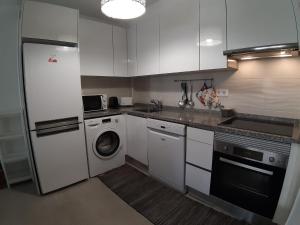モンテ・ゴルドにあるApartamento T2 Monte Gordoのキッチン(白いキャビネット、洗濯機、乾燥機付) +9枚の写真