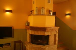sala de estar con chimenea de piedra y TV en Antico Casale San Lorenzo en Colle San Lorenzo