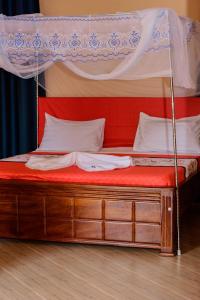 a bed with a canopy with a red mattress at NB MOTEL-KIHIHI in Kihihi