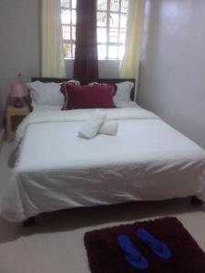 ein Schlafzimmer mit einem weißen Bett und blauen Hausschuhen darauf in der Unterkunft Emerald Gardens Airbnb in Kitale