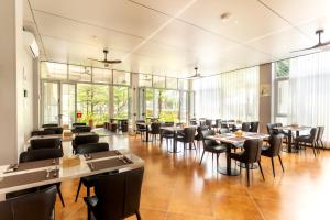 a restaurant with tables and chairs and windows at The Q Residence Vientiane in Vientiane