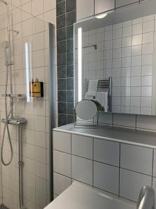 a bathroom with a shower and a mirror at Hotell Iföhus in Bromölla