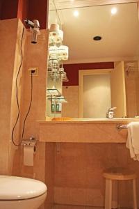 a bathroom with a toilet and a sink and a mirror at Hotel Al Sur De Chipiona by YouRoom in Chipiona