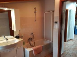 een badkamer met een bad, een wastafel en een douche bij Mansarda Dolomitica in Ronzo Chienis