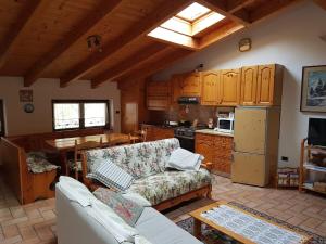 een woonkamer met een bank en een keuken bij Mansarda Dolomitica in Ronzo Chienis