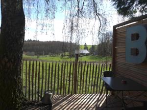 uma cerca com uma árvore e uma mesa em frente a um campo em Cabane bien belge avec cinéma et jacuzzi em Lasne