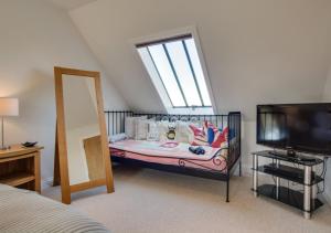 Schlafzimmer mit Kinderbett und TV in der Unterkunft Mulberry in Wells next the Sea