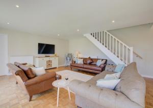 a living room with two couches and a staircase at Orchard Barn in Wighton