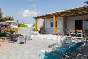 a patio with chairs and tables and a house at Villa Perla in Lardos