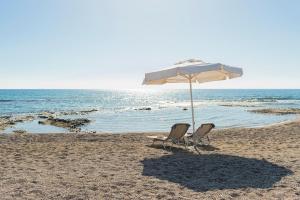 dwa krzesła i parasol na plaży w obiekcie Villa Perla w mieście Lardos