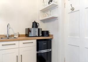 a kitchen with white cabinets and a black appliance at Palmers Folly in Wells next the Sea