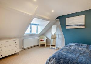 a bedroom with blue walls and a bed and a dresser at Quay View Cottage in Wells next the Sea