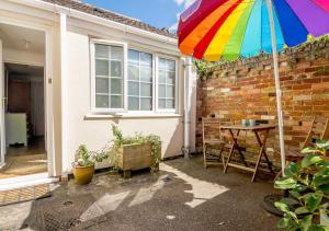 a rainbow colored umbrella in front of a house at The Annexe at Hideaway Cottage in Ellingham