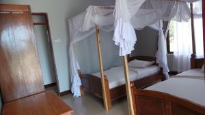 1 dormitorio con 2 literas y cortinas blancas en Ngalawa Bush Route Hostel, en Dar es Salaam
