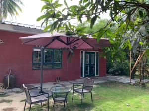 a table with chairs and an umbrella in front of a house at Fusion Villa in Bedung