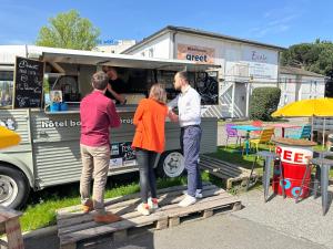 a group of people standing outside of a food truck at greet Hotel Bordeaux Aeroport in Mérignac