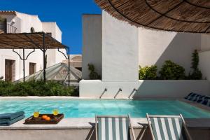 a pool with two chairs and a table with oranges on it at Casa del Rey Sabio in Seville +37 photos
