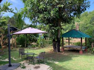 a table and chairs with an umbrella and a bench at Fusion Villa in Bedung