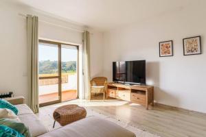 un soggiorno con un divano e una televisione di Odeceixe Valley Tranquility a Odeceixe