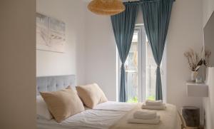 a bedroom with a bed with blue curtains and a window at Apartament MEWA SurfingBird Kołobrzeg in Kołobrzeg