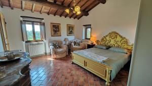 a bedroom with a bed and chairs in a room at Casale Alcinoo - Rustico in Tuoro sul Trasimeno