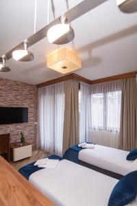 Habitación de hotel con 2 camas y lámpara de araña. en Central Inn en Zlatibor