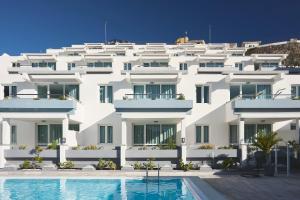 a white building with a swimming pool in front of it at Mariposa Del Sol in Patalavaca