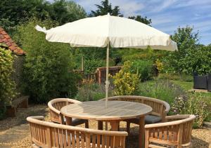 una mesa de madera con una sombrilla en el jardín en Golden Lion Barn en Thursford